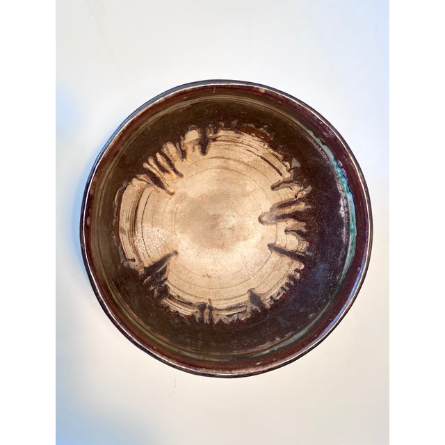 Deep, handcrafted, and signed bowl in dark earth tones. The interior surprises with a vibrant gradient glaze and a...