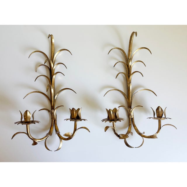 A stunning pair of vintage Hollywood Regency style gilded toleware metal wall sconces, likely crafted in Italy or France...