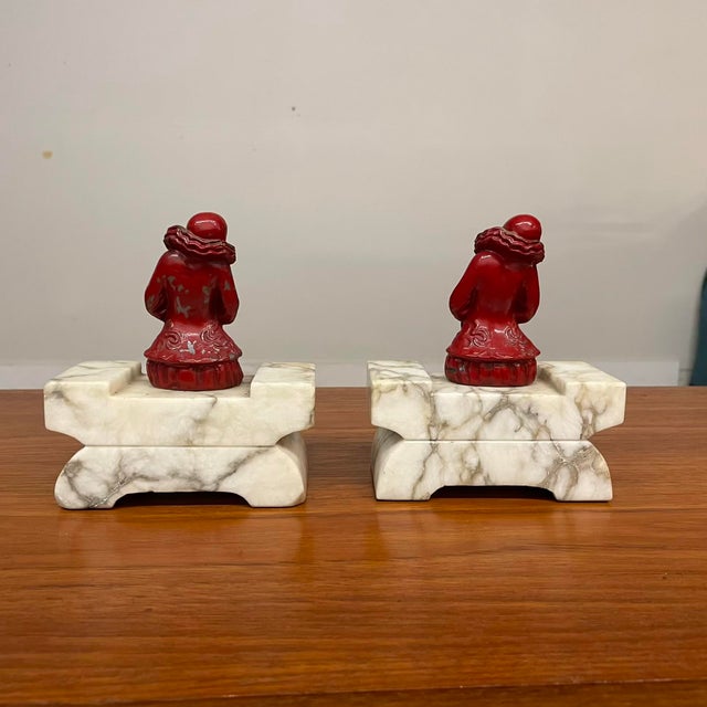 This elegant pair of 1920s French Art Deco bookends features seated Pierrot figures resting on tiered gray marble bases....