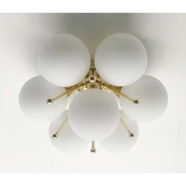 Italian flush mount with seven matte white Murano glass globes mounted on solid brass frame in lacquered polished brass...