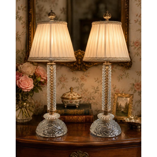 A charming pair of vintage crystal table lamps featuring heavily cut crystal bases, diamond-point faceted columns, and...