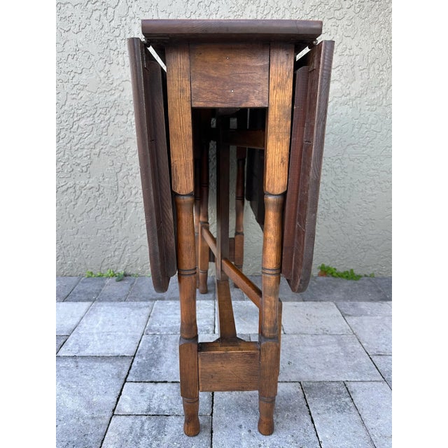 Wood gate leg table with 2 drop leaf sides. Two hook and eye latches on the bottom side of each leaf. When completely...