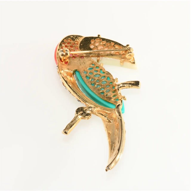 Vintage brooch in the shape of a bird, specifically a toucan, with resin components in ivory, coral, and turquoise blue...