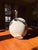 This ceramic vessel features an intricate design of four serpents, their forms elegantly entwined around the surface. The...