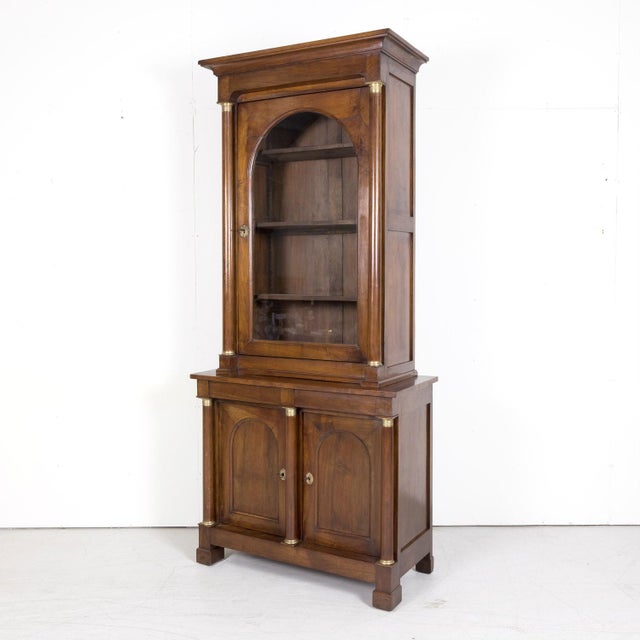 A fine early 19th century French Empire period bibliothèque or bookcase handcrafted of select walnut by talented artisans...