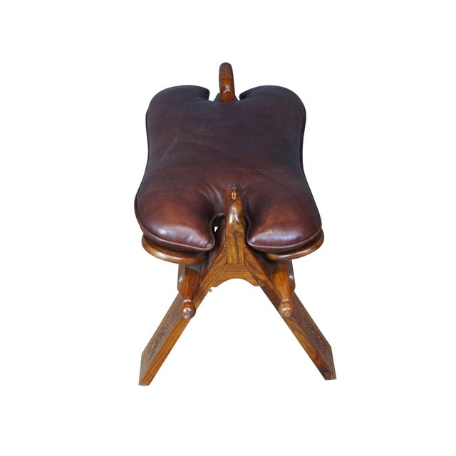 Mid century camel seat stools. Made of Rosewood featuring a carved floral accents with brown leather seat, two handles and...