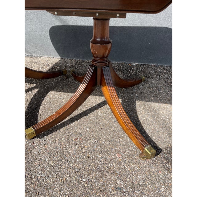 Beautiful circa 1920s antique mahogany dining table, featuring a classic English Regency / Duncan Phyfe-inspired design....