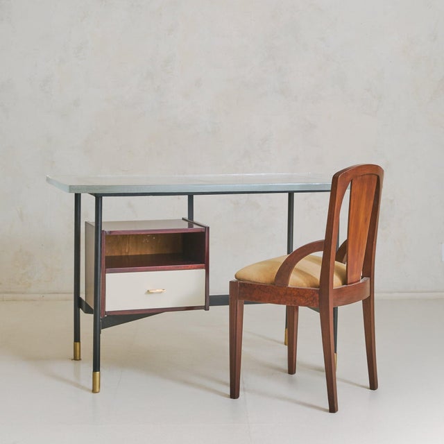 An Italian desk from the 1950s, attributed to Luigi Caccia Dominioni for Azucena, distinguished by a thick cast glass top...