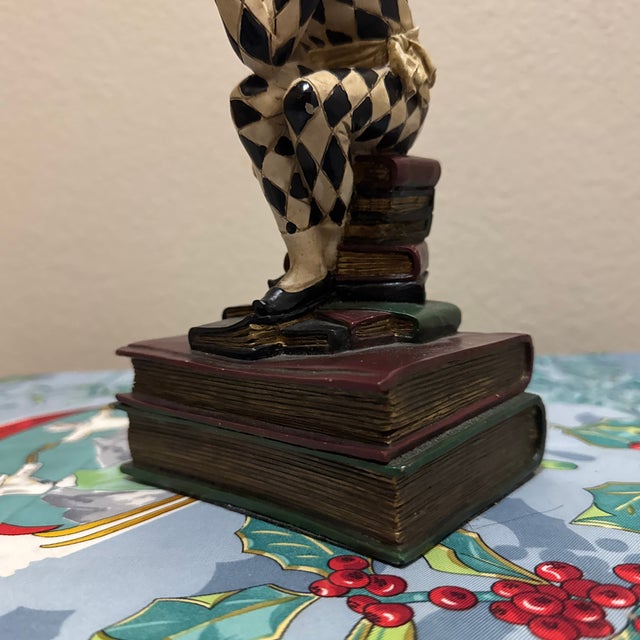 A charming and highly detailed vintage bookend depicting a Harlequin or Jester in a classic "Thinker" pose. Exuding the...
