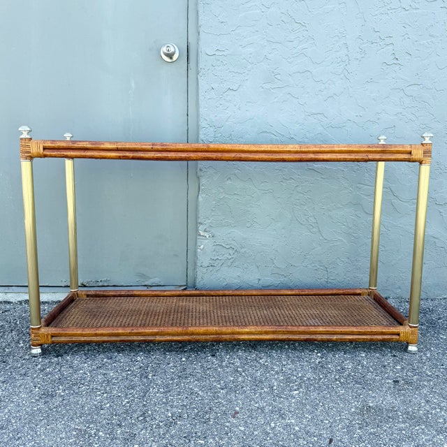 A fabulous vintage Palm Beach Chic console table combining warm rattan, woven cane, glass, and gold-tone accents. The...