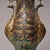 This decorative bronze vase features twin peacock‑form handles, intricately carved peacock feather patterns across the...