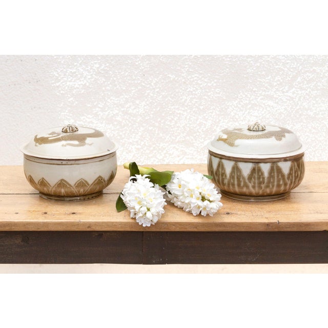 This elegant set of two porcelain jars with lids, each measuring 8 inches in diameter and 5.5 inches high, features a...