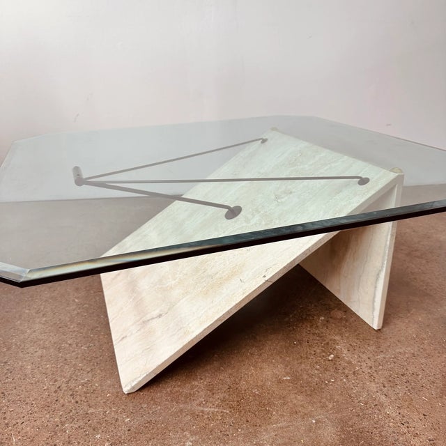 Vintage post modern or modernist style angular coffee table. Features a travertine and offset black 3 prong metal support...