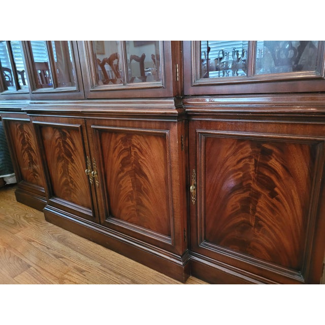 This beautiful breakfront bookcase cabinet features mahogany inlay and elegant brass pulls. The top consists of a four...