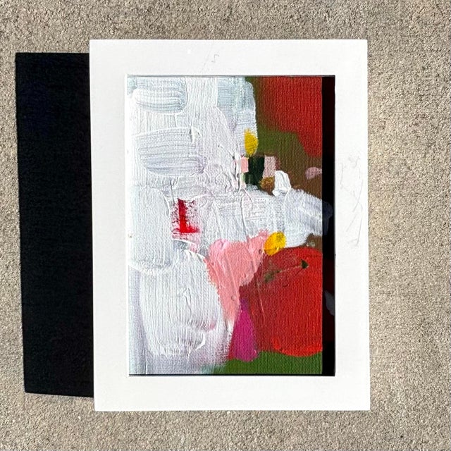 This small abstract painting features soft, layered strokes of red, green, and soft white, with subtle hints of warm beige...