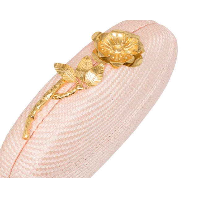 The JOANNA Oval clutch is an ode to enduring elegance, crafted from handwoven pale pink buntal and crowned with a gold-...