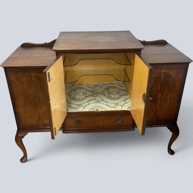 An elegant Art Deco walnut cocktail cabinet that bridges the clean geometry of the 1930s with graceful Queen Anne-inspired...