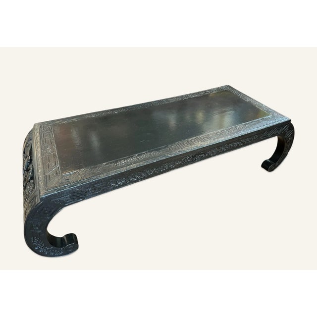 1920s Chinese black lacquered coffee table carved with vignettes of court scenes with abundant prunus blossoms. This table...