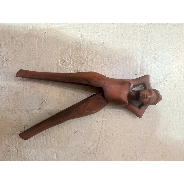 legant hand-carved wooden figural nut opener depicting a reclining female form with elongated, sculptural lines. Likely of...