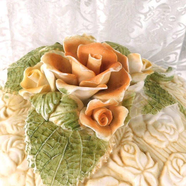 This is a large unmarked white ceramic or porcelain bowl with a matching lid. The bowl is unglazed and has a raised flower...