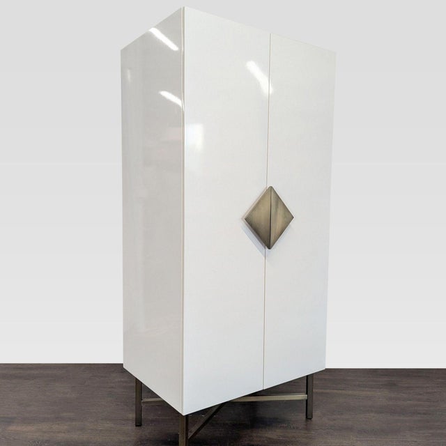 The wardrobe stands on steel legs with a wood frame that supports one fixed shelf with a removable brass pole for hanging...