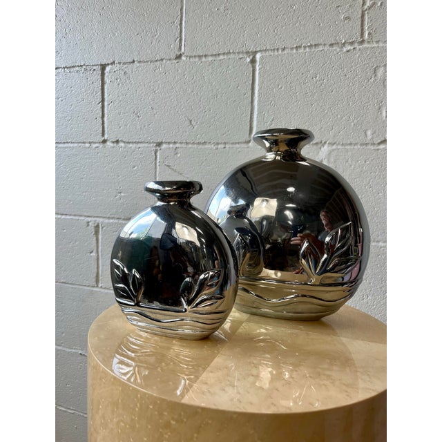 A striking pair of Art Deco Revival vases by Dolbi Cashier, crafted in cast metal with a highly polished gunmetal finish....