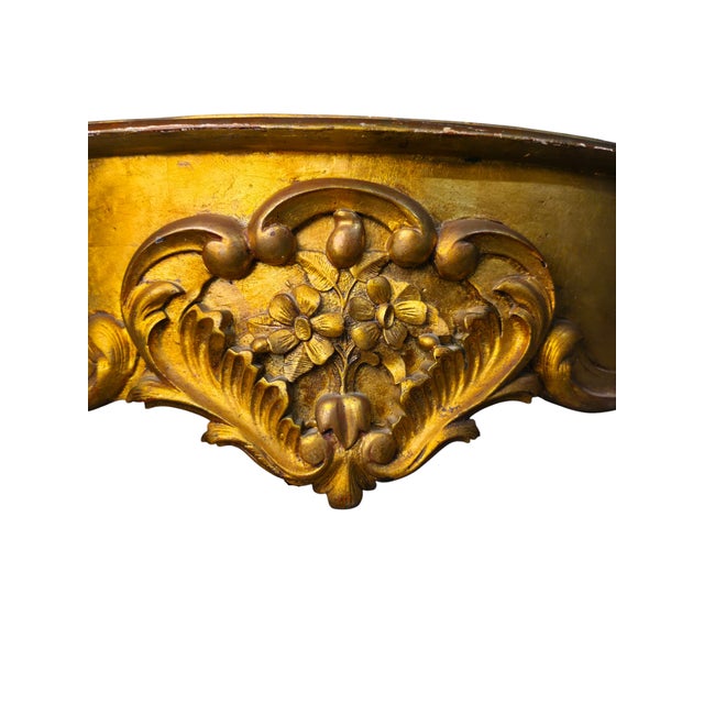 An ornate vintage Louis XV-style console table featuring a sculptural gold-finished wood frame, dramatically shaped apron...