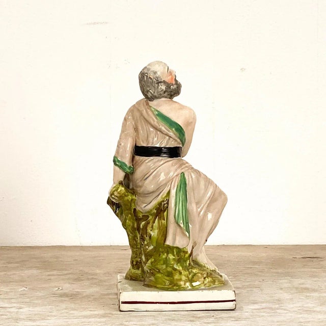 An early 19th Century English Staffordshire of Elijah and the Raven, circa 1800. The figure of Elijah is dressed in a...