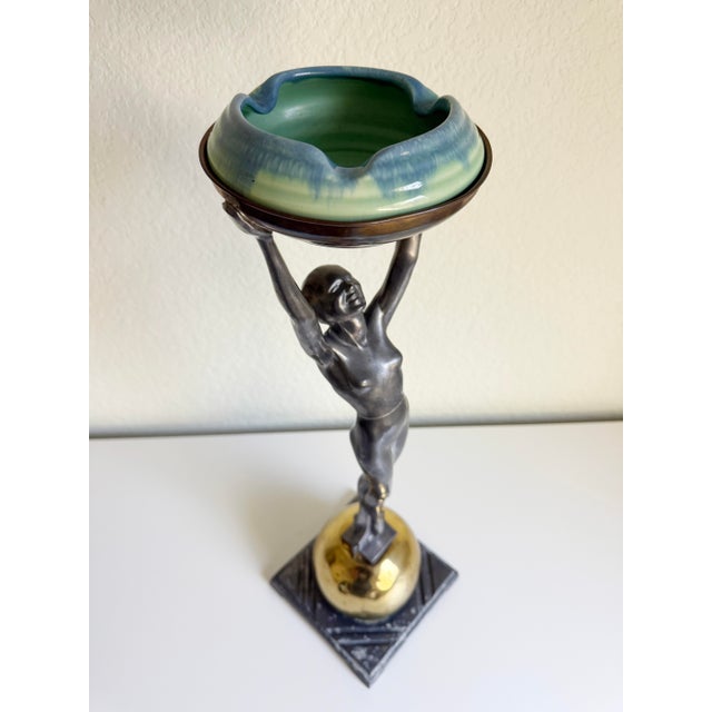 An original 1920s Art Deco "Standing Nude on Ball" sculptural floor ashtray stand with ceramic insert, designed and...
