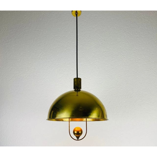 Extraordinary polished brass pendant lamp designed by Florian Schulz and made in Germany in the 1970s. It is fascinating...