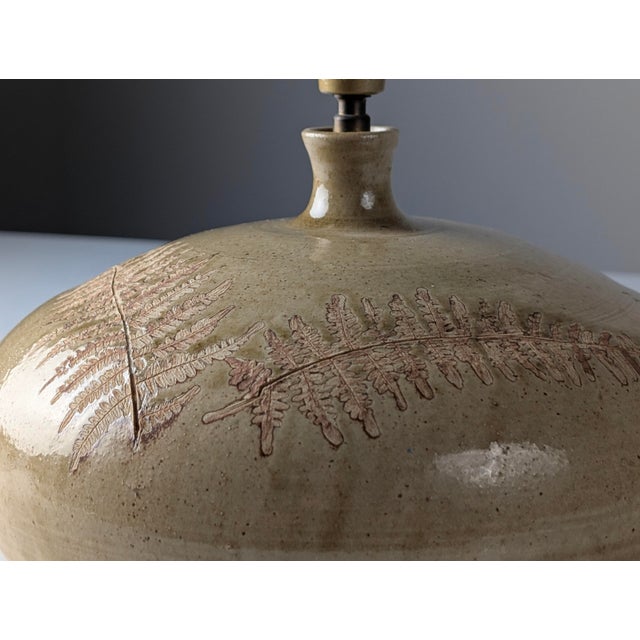 This table lamp is made of glazed ceramic in the style of Roger Capron, reminiscent of the pottery associated with...