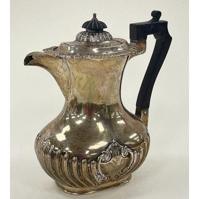 An elegant antique English sterling silver coffee pot by the distinguished Sheffield silversmiths John Round & Son, dating...