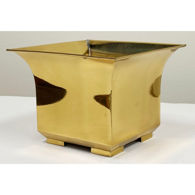 Vintage postmodern style brass planter featuring a square body, smooth frame and curved lip at top. Footed. Nice patina...