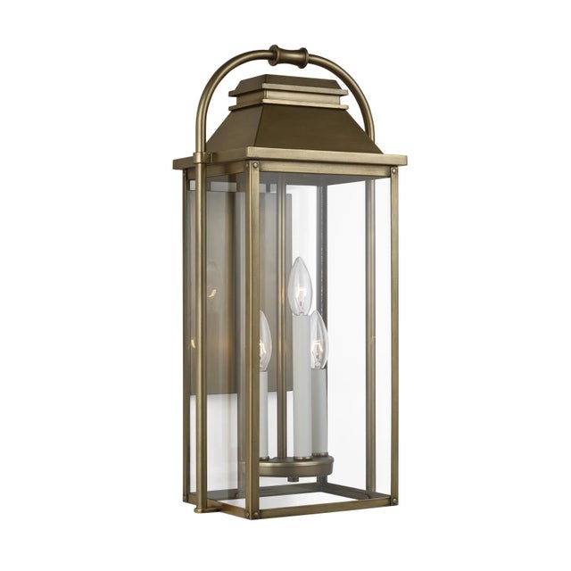 The Sean Lavin Wellsworth three light outdoor wall fixture in painted distressed brass creates a warm and inviting welcome...