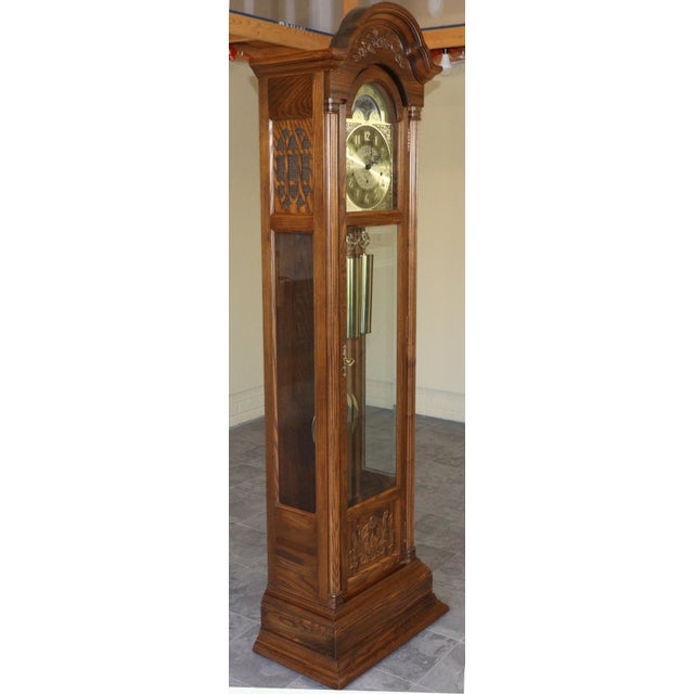 An elegant vintage Seth Thomas grandfather clock distinguished by its richly grained wood case, sculpted floral ornament,...