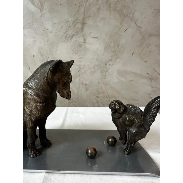 An elegant Art Deco bronze animal sculpture depicting a dog observing a squirrel with two small spheres, in a composition...