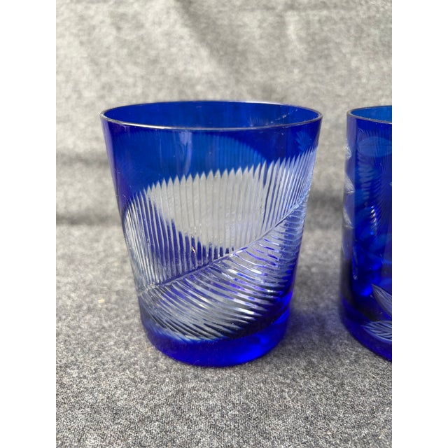 Vintage set of 2, mismatched, cut to clear, cobalt blue tumblers. One has a large leaf design, the other a branch with...