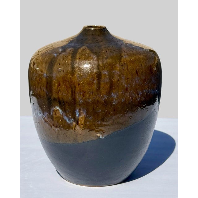 A vintage studio pottery vase featuring a drip glaze, also known as tenmoku glaze, with a glossy mottled brown and orange...