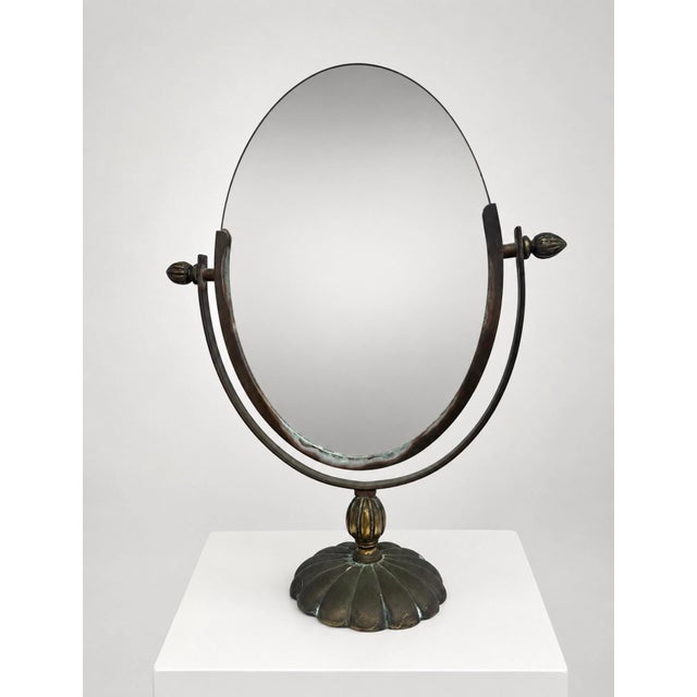 Vintage solid brass tabletop vanity mirror with an oval double-sided swivel mirror, sculptural shell-form base, ribbed...