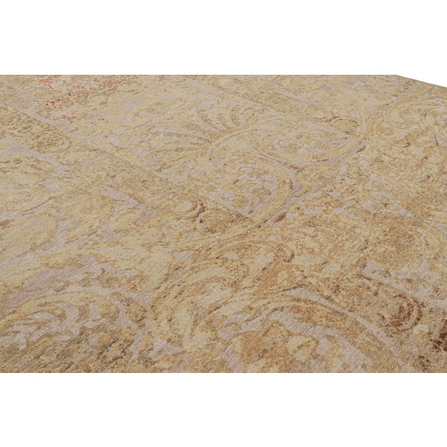 Hand-knotted in wool, this 10x14 modern European rug, originating from India, as inspired by grand European designs of...