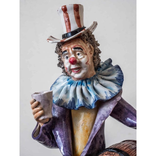 Hand-painted statue of a clown with barrels and a cup in his hand. The statue is signed on the back and marked on the...