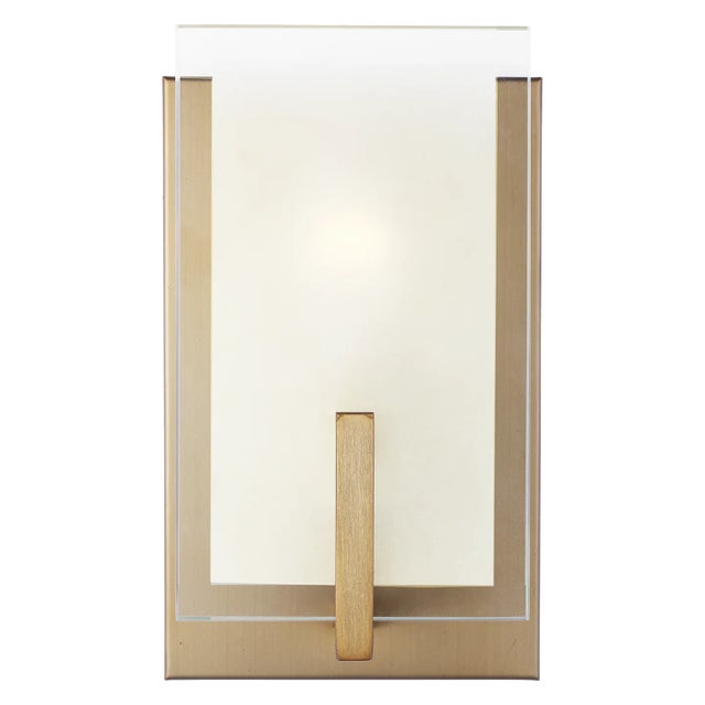 The Syll one light wall sconce in satin brass offers shadow-free lighting in your powder room, spa, or master bath room....