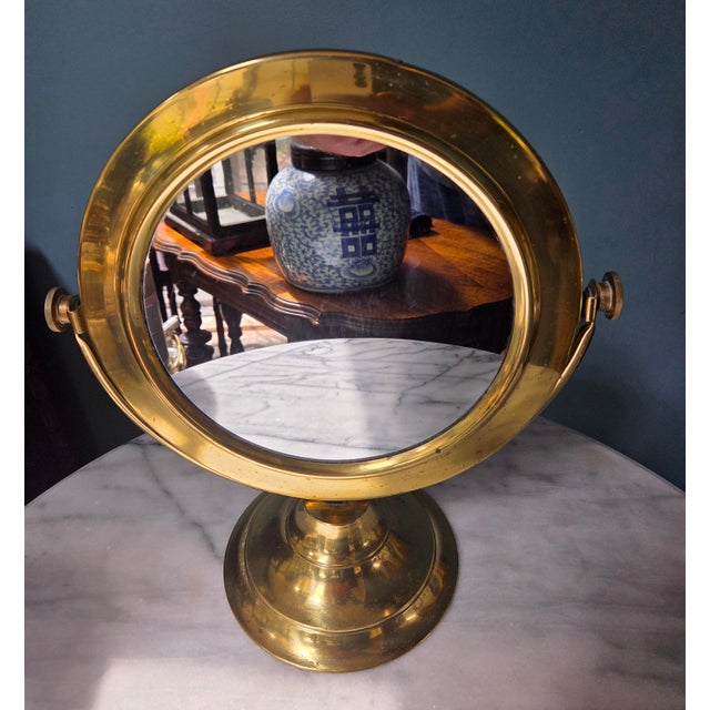 Classic vintage brass tabletop mirror. Crafted with a timeless silhouette, this piece beautifully balances functional...