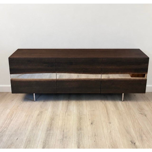Seared oak sideboard featuring a broad horizontal inlay of high polished stainless steel bordered with live edge oak....