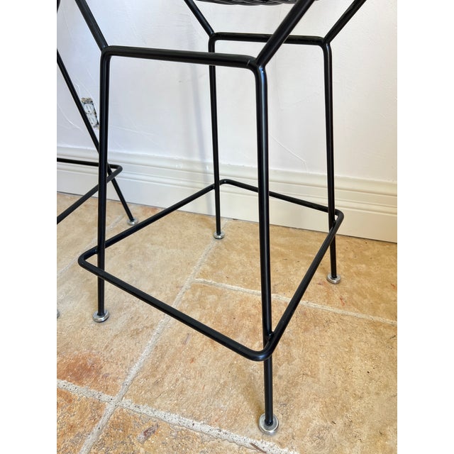 Iconic black wire bar stools designed by Harry Bertoia for Knoll featuring a grid construction seat and back sculpted from...