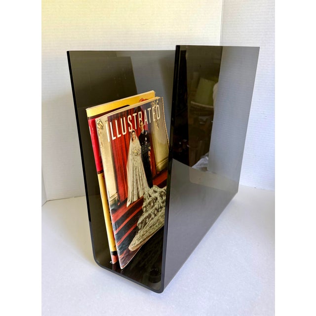 Here is a vintage, Postmodern/Modern later 20th-century magazine rack crafted from translucent smoked gray Lucite with a...