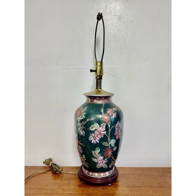 1970’s Vintage Asian-inspired ceramic ginger jar table lamp with hand-painted floral décor and wood base. Tested and...