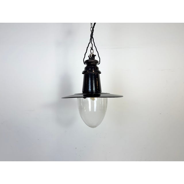 Industrial black enamel pendant light made in German during the 1930s. White enamel inside the shade. Clear glass cover....
