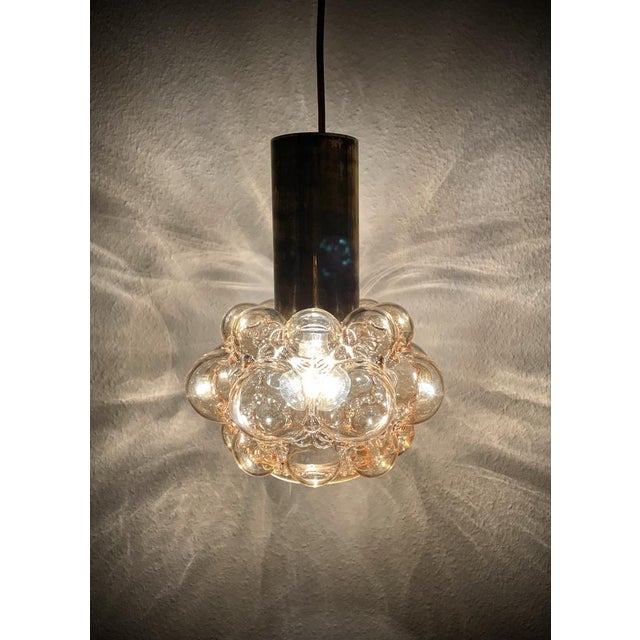 A stunning 1970s pendant lamp designed by helena tynell for limburg glashütte, featuring the iconic “bubble” glass design....