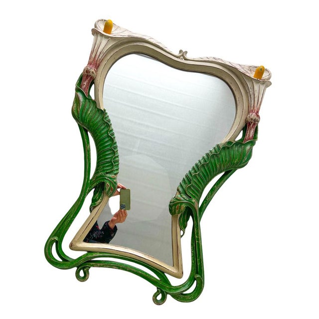 An ornate antique French Art Nouveau mirror with wood carving and authentic painting. At the heart of the allure of this...